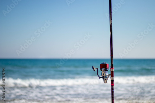 fishing rod held in the sand while the fisherman fishes