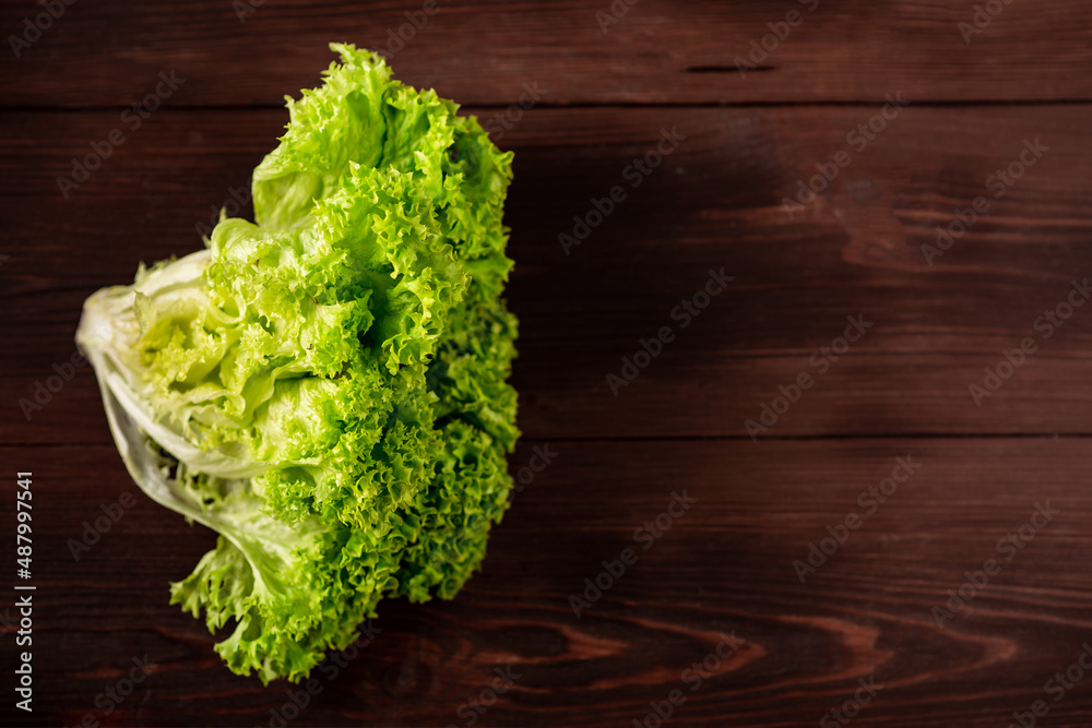 Green lettuce salad on a wooden background. Vegetarianism concept, plant food. Place for text. Green lettuce salad on a wooden background. Vegetarianism concept, plant food. Place for text.
