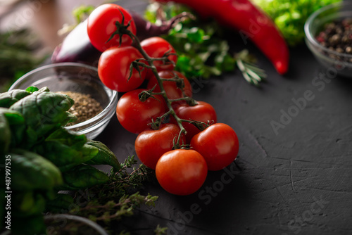 Branch of cherry tomatoes. Dark background. Various vegetables. Vegetarian food. Raw food diet.