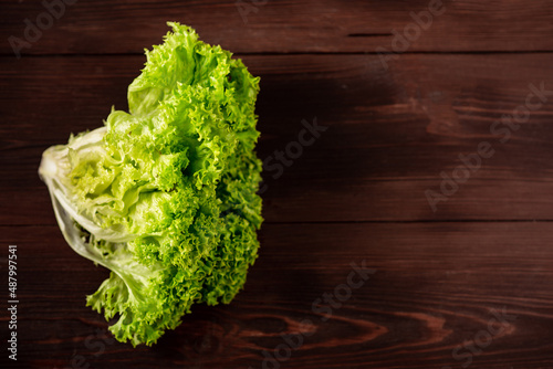 Green lettuce salad on a wooden background. Vegetarianism concept, plant food. Place for text.