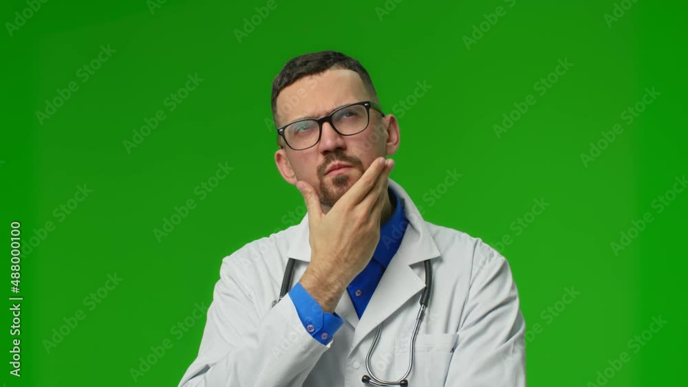 Serious thoughtful male doctor rising his head and looking up. Isolated, on green background. Serious thoughtful male doctor rising his head and looking up. Isolated, on green background.