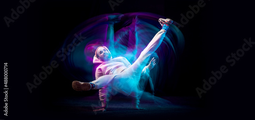 One energy young flexible sportive man dancing hip-hop or breakdance in white outfit on dark background in mixed blue neon light. Sport, art, action, moves © master1305