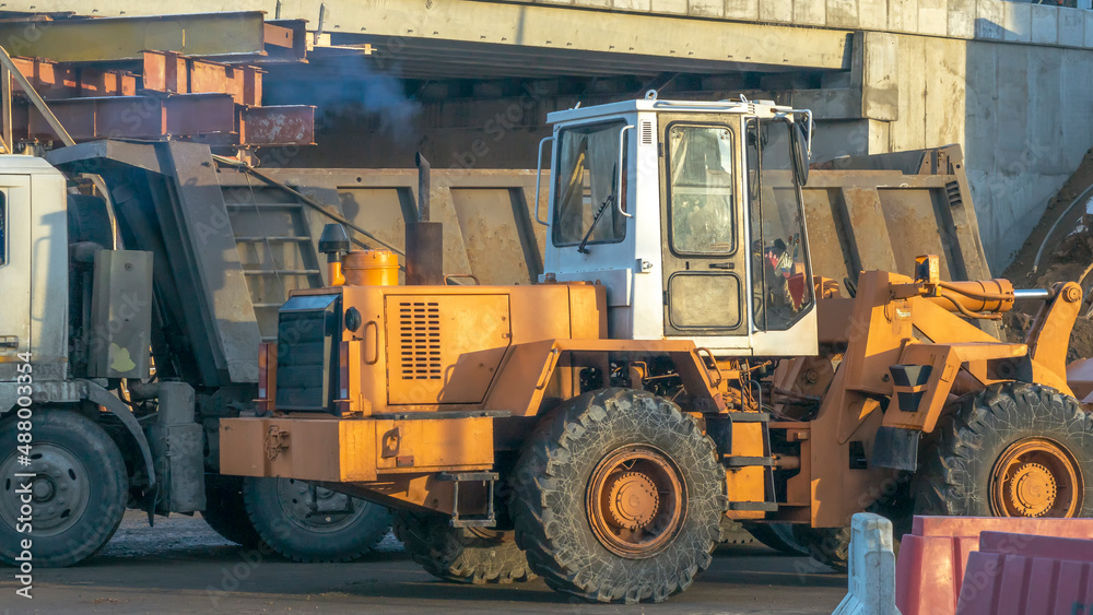 Motor grader on road construction. Orange bulldozer on bridge road construction site. Detour. Road Closed.