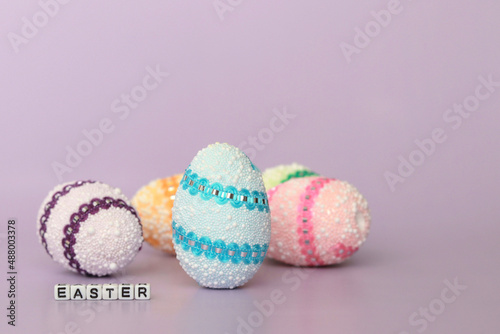 Decorative multicolored Easter eggs, easter inscription on a purple background, Easter holiday concept