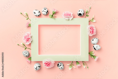 Happy Easter concept. Frame of Easter eggs and spring flowers on pink paper background. Flat lay, copy space.