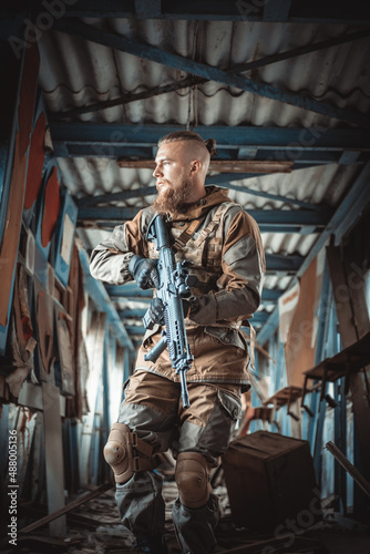 a male military soldier in an abandoned building with a gun poses, shoots and takes aim © Алевтина Шевченко