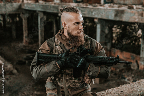 a male military soldier in an abandoned building with a gun poses, shoots and takes aim