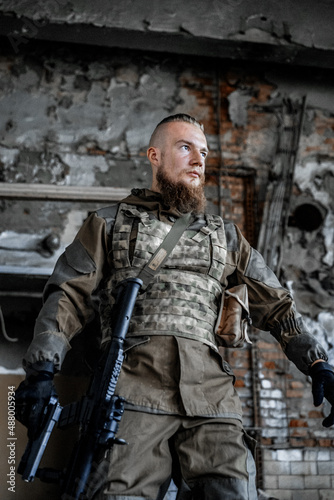 a male military soldier in an abandoned building with a gun poses, shoots and takes aim