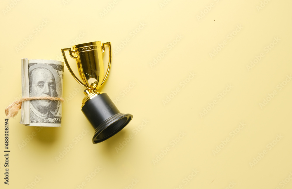 A picture of fake money with broken trophy on copyspace yellow background. Sports corruption concept.