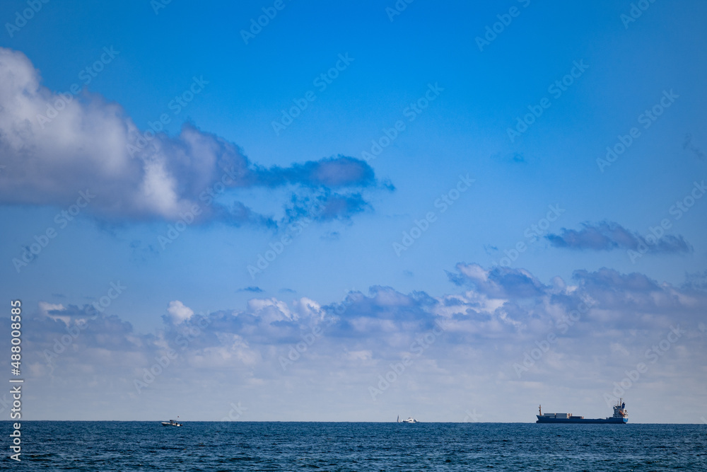 Freight boat and small naval vessels on the horizon of the Fort Lauderdale ocean shore