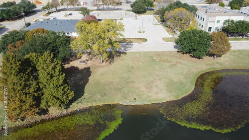 Top view office building and commercial warehouse near algae blanket lily pad pond in Carrollton Texas, USA