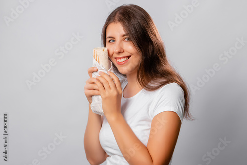 A girl in a white t-shirt holds shawarma in her hands isolated on a white background, mockup.