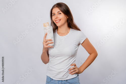 A girl in a white t-shirt holds shawarma in her hands isolated on a white background, mockup.