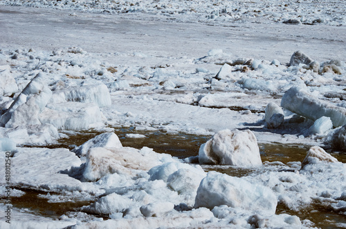 Ice drift on the Amur River. Melting ice floes in spring. A heap of blocks and fragments. Sunny day.