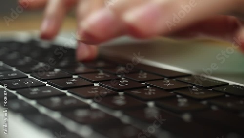 Close-up of woman hands typing on a laptop keyboard. Slow motion footage