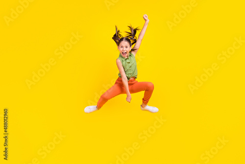 Photo of funky charming preteen girl dressed green top jumping high riding horse throwing lasso smiling isolated yellow color background