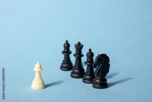 One chess piece against black chess pieces on a blue background with contrasting shadows. Abstract background. Concept of leadership photo