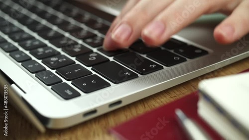 Close-up of woman hands typing on a laptop keyboard. Slow motion footage