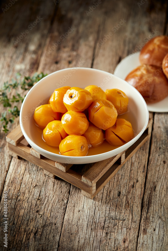 Homemade sweet peaches, a typical Ecuadorian dessert served on a white plate with a wooden and rustic background