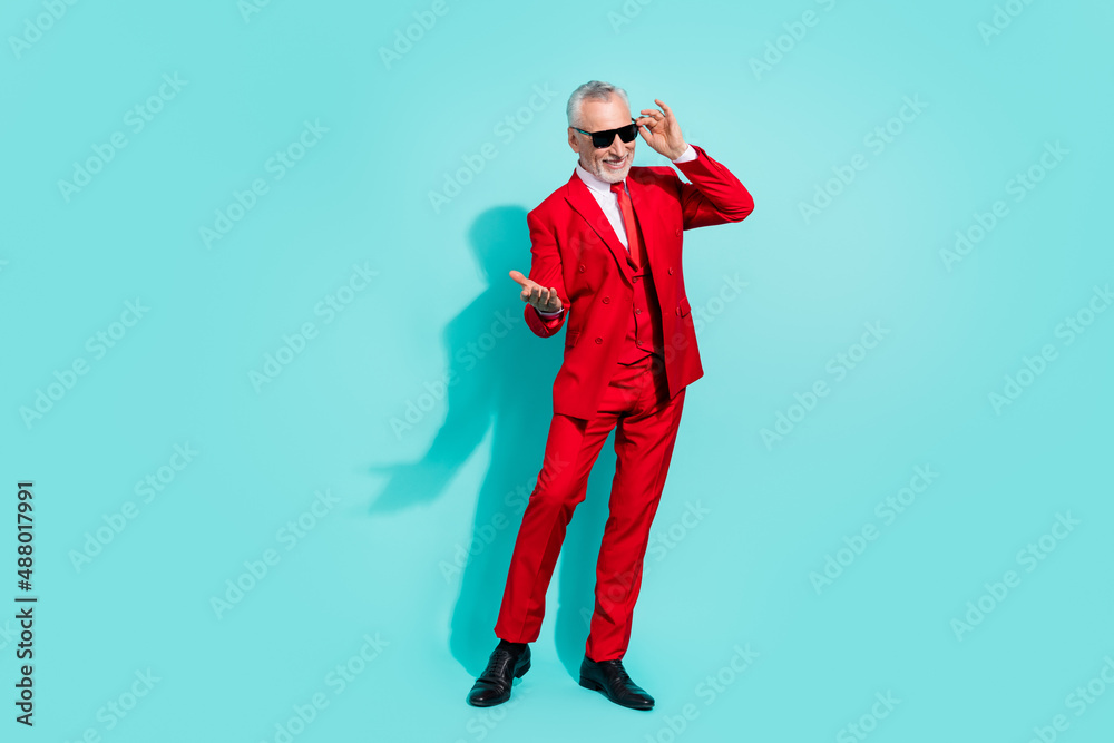 Photo of funky retired man wear red suit dark eyewear inviting you dance isolated turquoise color background Photo of funky retired man wear red suit dark eyewear inviting you dance isolated turquoise color background