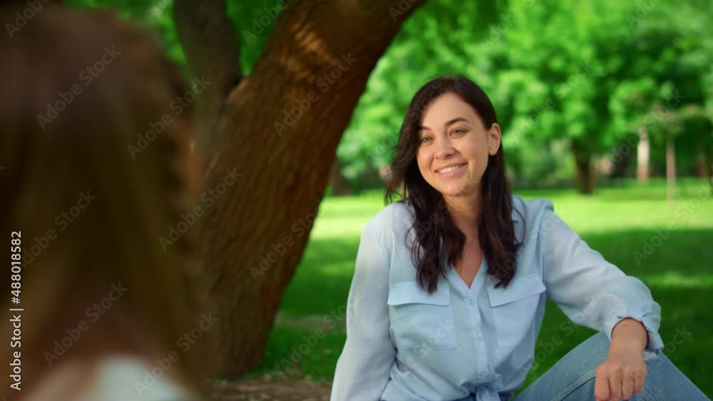 Smiling woman sitting on grass in park closeup. Tranquil mother posing on nature Smiling woman sitting on grass in park closeup. Tranquil mother posing on nature