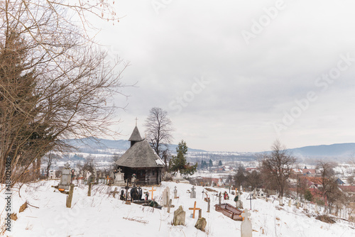 Old Saxon cemetery near wooden church in the winter, church historical monument in Sinca Noua village, Transylvania Brasov region, Romania photo