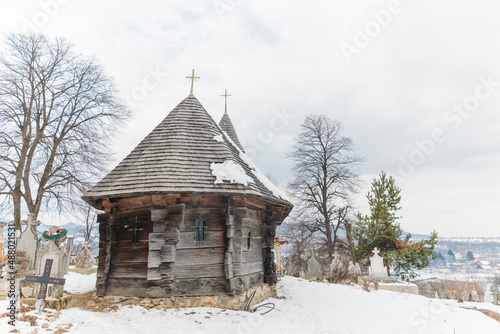 Wooden church with snow atop its steeple is an architectural gem among the small community of residents and cemetery just outside of Brasov in Transylvania © Damian