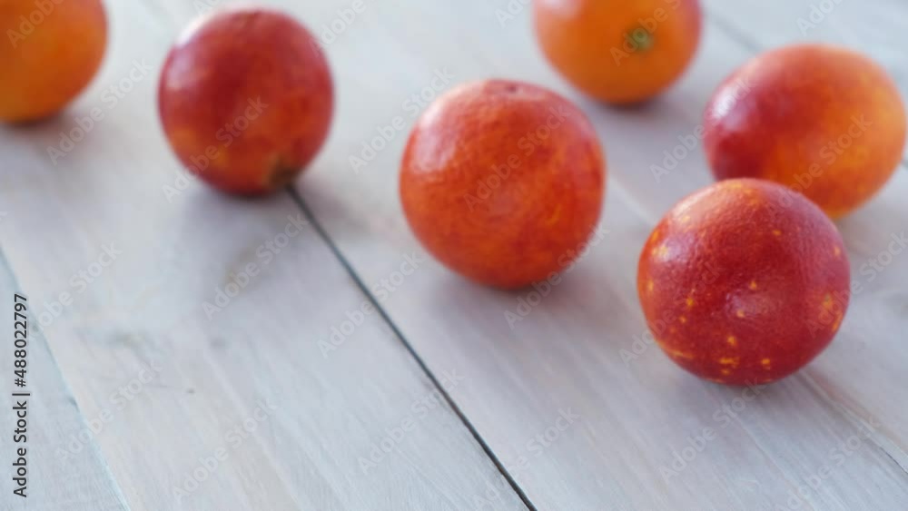 Woman's hands cut knife ripe juicy Sicilian blood red oranges on wooden background. Seasonal fruits. Close-up. Concept: organic fruits, healthy food. . High quality 4k footage Woman's hands cut knife ripe juicy Sicilian blood red oranges on wooden background. Seasonal fruits. Close-up. Concept: organic fruits, healthy food. . High quality 4k footage