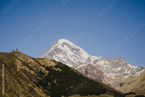 A beautiful mountain landscape with a blue sky. Snow-capped peak of Mount Kazbek in Stepantsminda Georgia