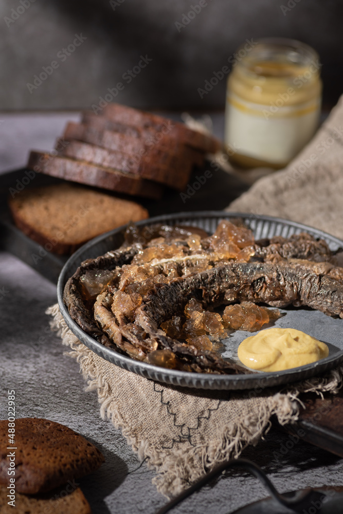 Selective focus baked lamprey in black tea jelly with mustard traditional Latvian cousins  