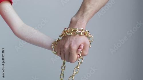 A child and a man hands are tied with a golden chain, holding and not letting go