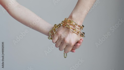 A woman and a child hands are tied with a golden chain, holding and not letting go