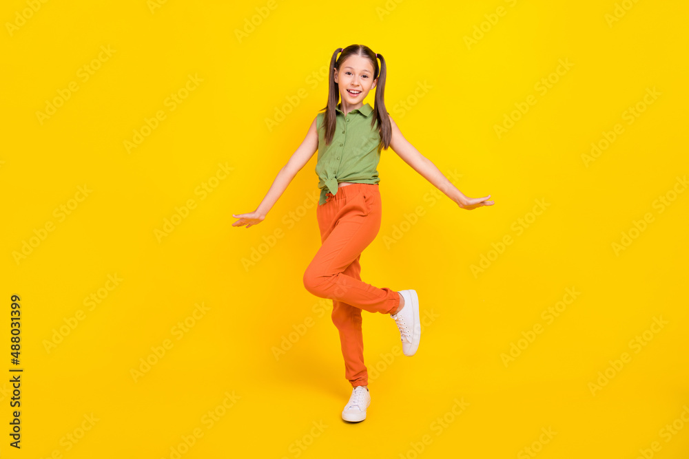 Photo of funny childish preteen girl dressed green top walking smiling isolated yellow color background