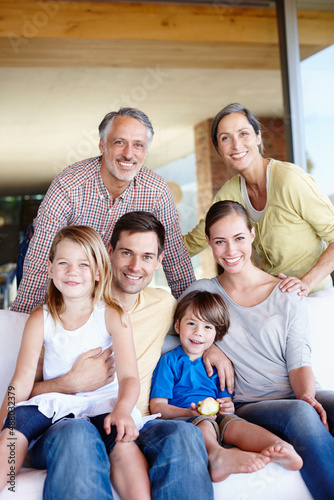 Three generations of love. A portrait of a happy multi-generational family gathered at home in their living room.