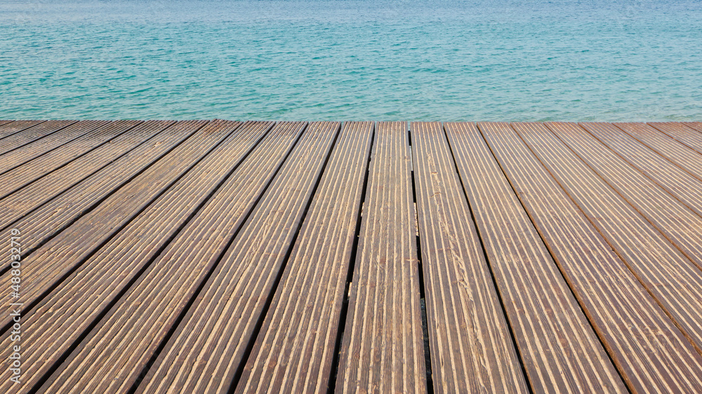 Contrasting textures of a wooden jetty made of aged wood and a smooth surface of deep blue water Contrasting textures of a wooden jetty made of aged wood and a smooth surface of deep blue water