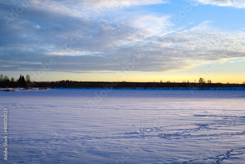 View of the part of the Volga River frozen and covered with a thick layer of snow during the January sunset. Fishermen s footprints are visible in the snow.