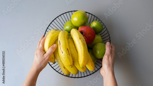 Fotografie hands holding fruit basket. Orange, apple, banana, mango, lemon.