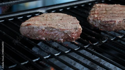 Steaks Being Turned on a Barbecue Grill with Lid Closing