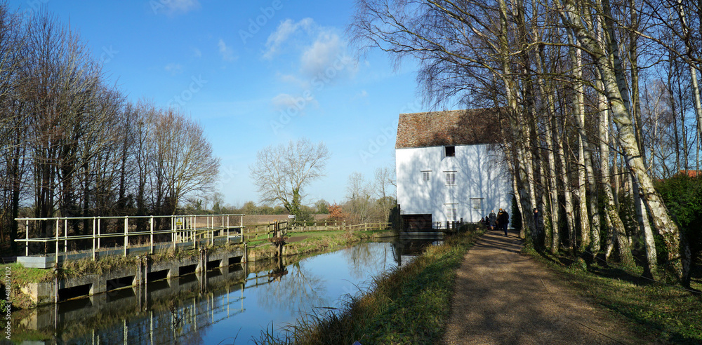 Watermill and Mill stream at Lode in Cambridgeshire with trees and blue sky.
