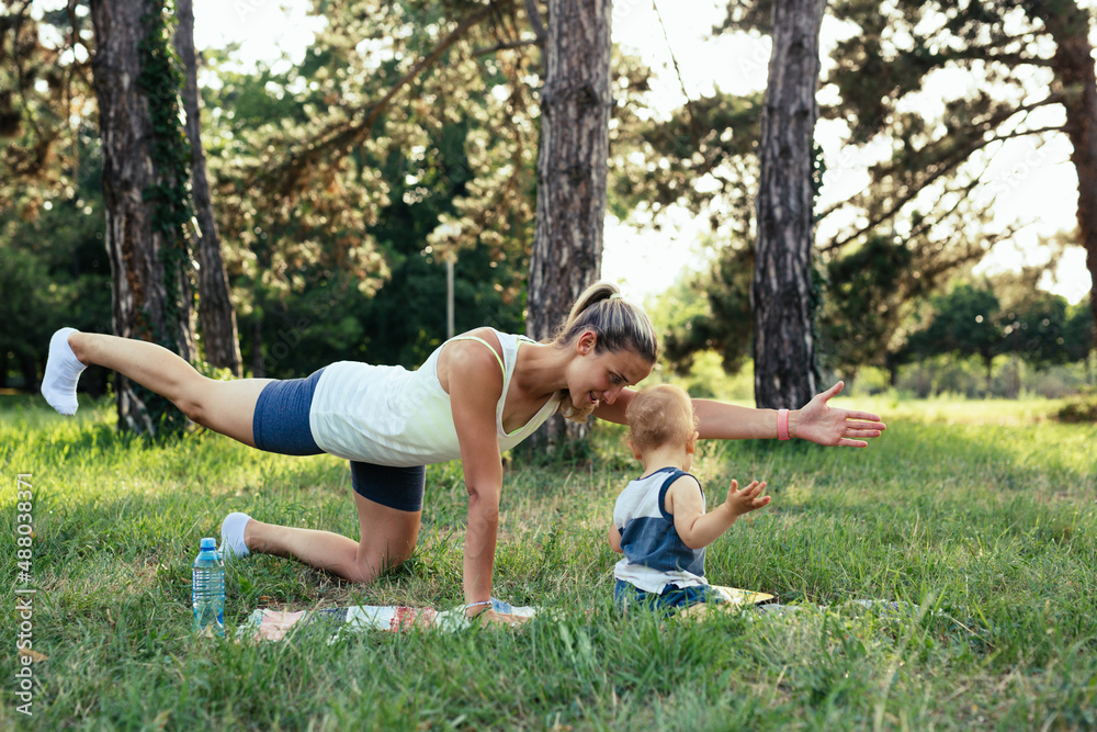 mother and her baby boy physical exercise in public park