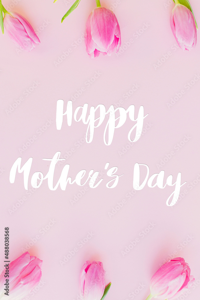 Happy mothers day text on pink tulips flat lay on pink background. Stylish greeting card. Happy Mother's Day, gratitude and love to mom. Handwritten lettering