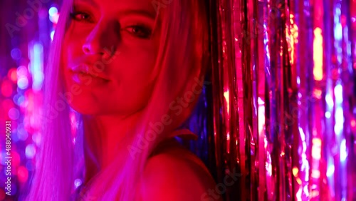 charming blonde woman in nightclub, lady is flirting and playing with shiny tinsel, portrait photo