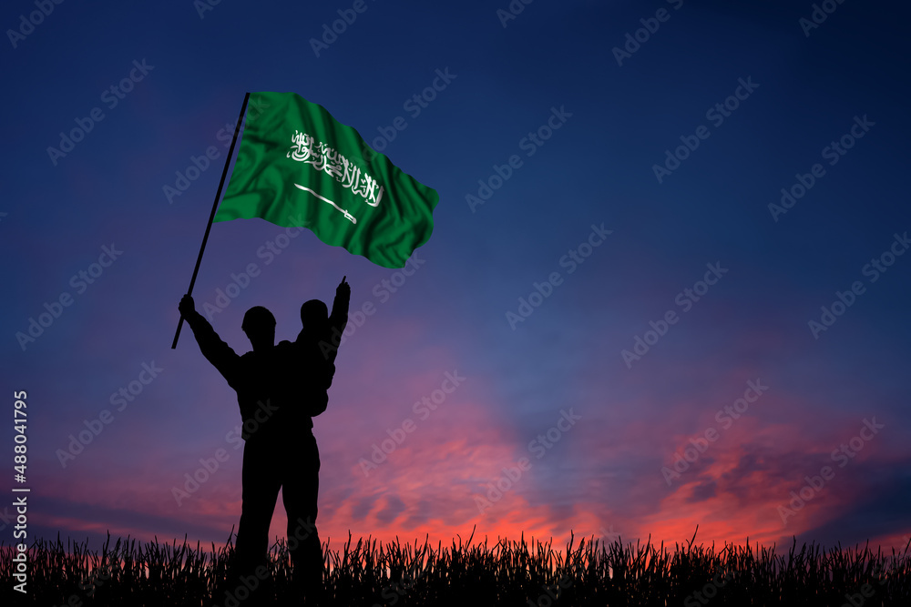 Father and son hold the flag of Saudi Arabia