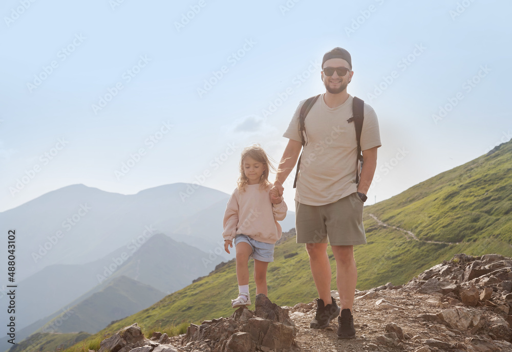 Father with child walking on the mountain and enjoying beautiful view. Family hiking.