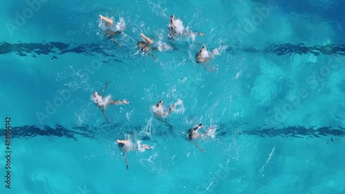 Aerial view of group synchronized swimmers performance with legs