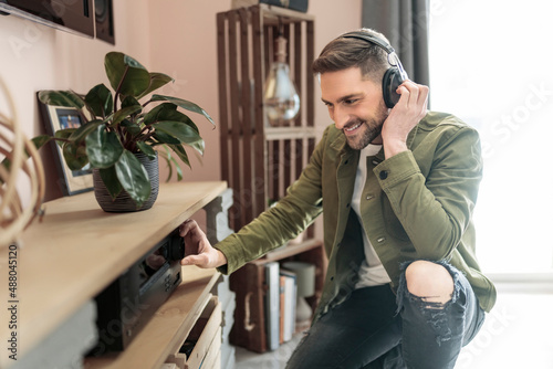 Photos Handsome guy wearing headphones enjoys music in front of his stereo system