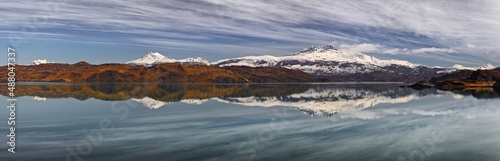 Ultra wide panorama of a landscape with snow covered mountains reflecting in a lake (Lago Pehoe) in Patagonia, Chile © Chris