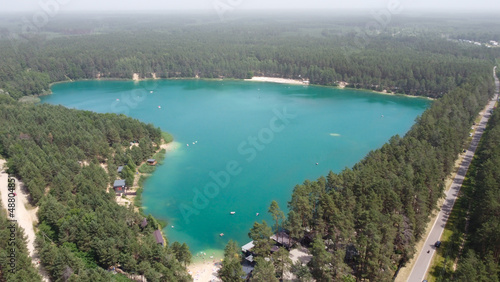 Beautiful Blue Lake looks as heart-shaped, dron photo. Aerial view of romantic nature blue lough with beach between green forests on sunny summer day with aerial perspective, Ukraine, bird's-eye view.