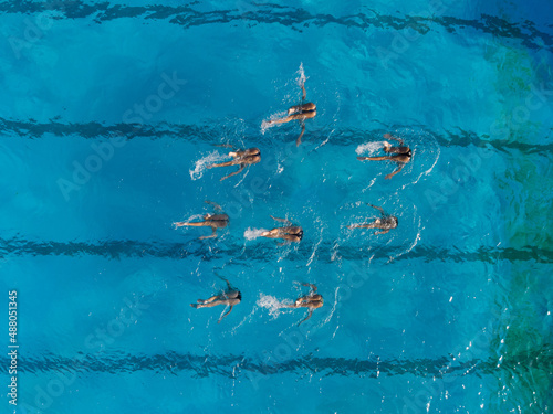 фотографія Aerial view of group synchronized swimmers performance with legs