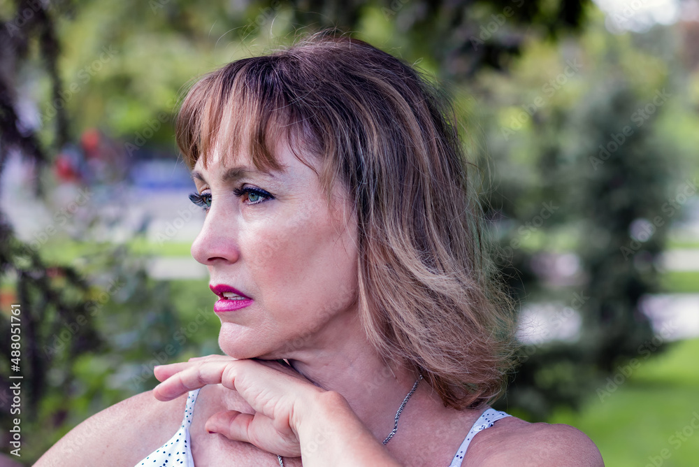 portrait of a beautiful middle-aged woman, 50-55 years old, in profile, against the backdrop of green nature portrait of a beautiful middle-aged woman, 50-55 years old, in profile, against the backdrop of green nature